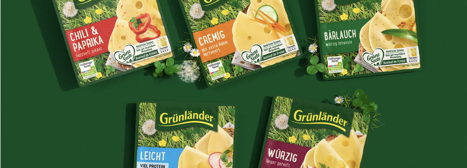Grünländer cheese packaging with herbs and flowers against a green background.