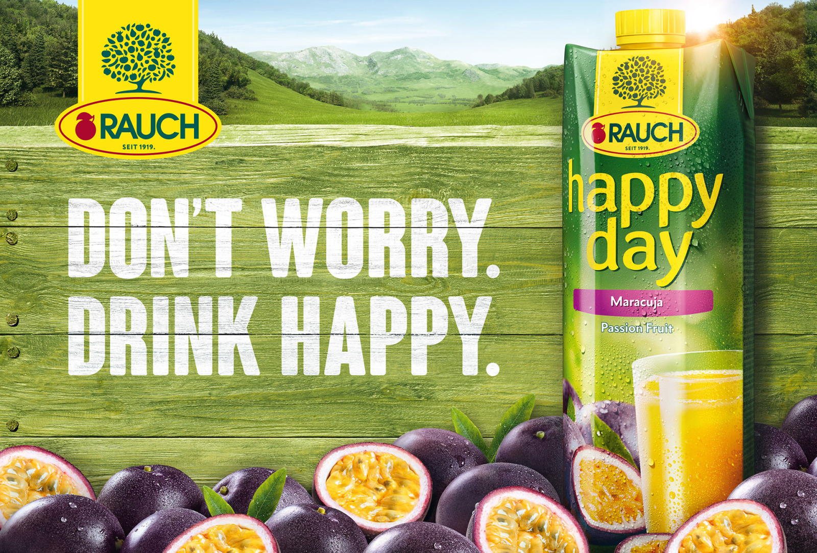Rauch Happy Day passion fruit juice carton with fresh passion fruit against a green countryside background.