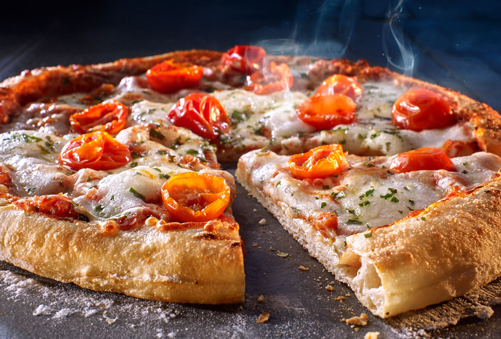 Close-up of a hot Wagner pizza with melted cheese, tomatoes and a golden crust.